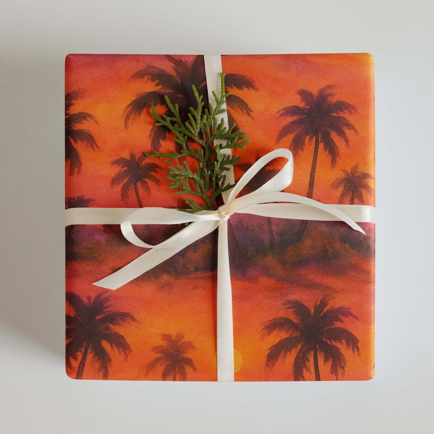 Luxury Christmas wrapping paper featuring a tropical sunset watercolor design with palm trees.