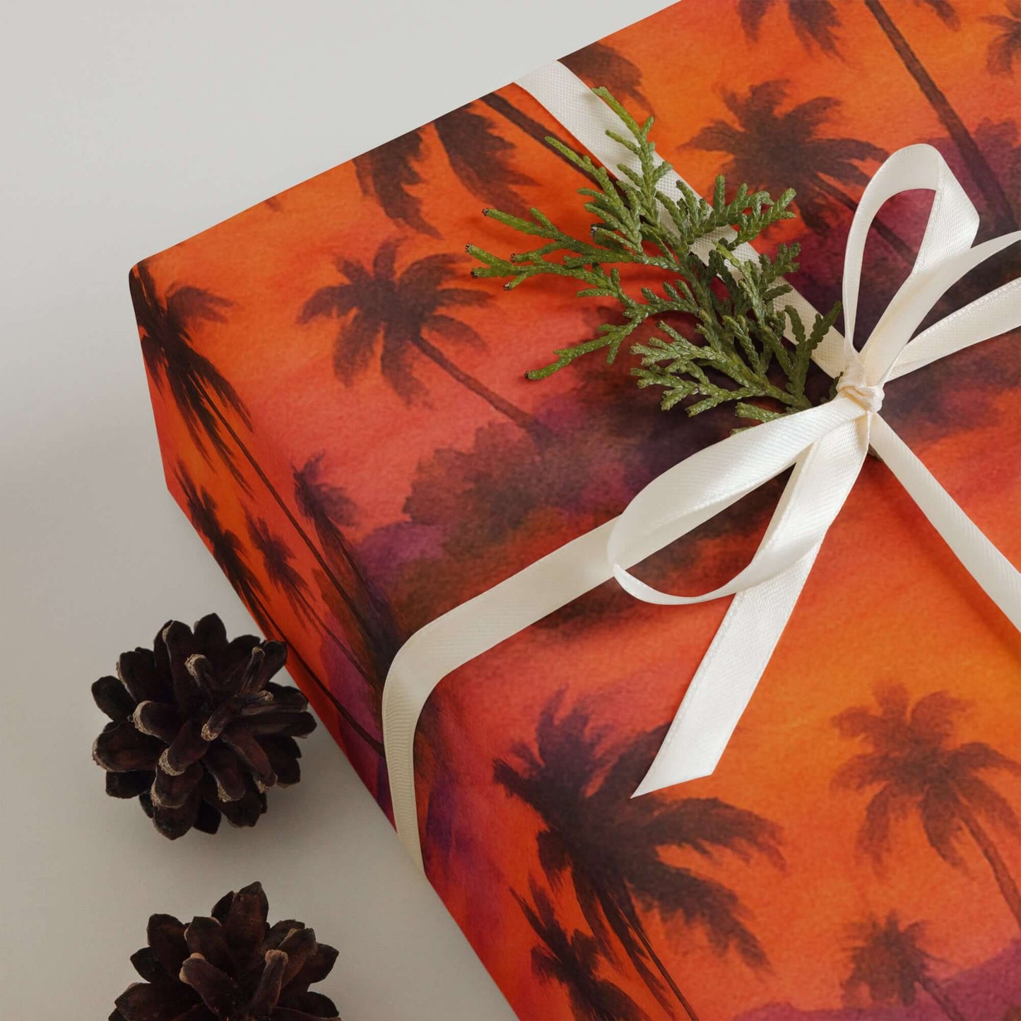 Luxury holiday gift wrap featuring watercolor beach sunset design with palm trees and a decorative bow.
