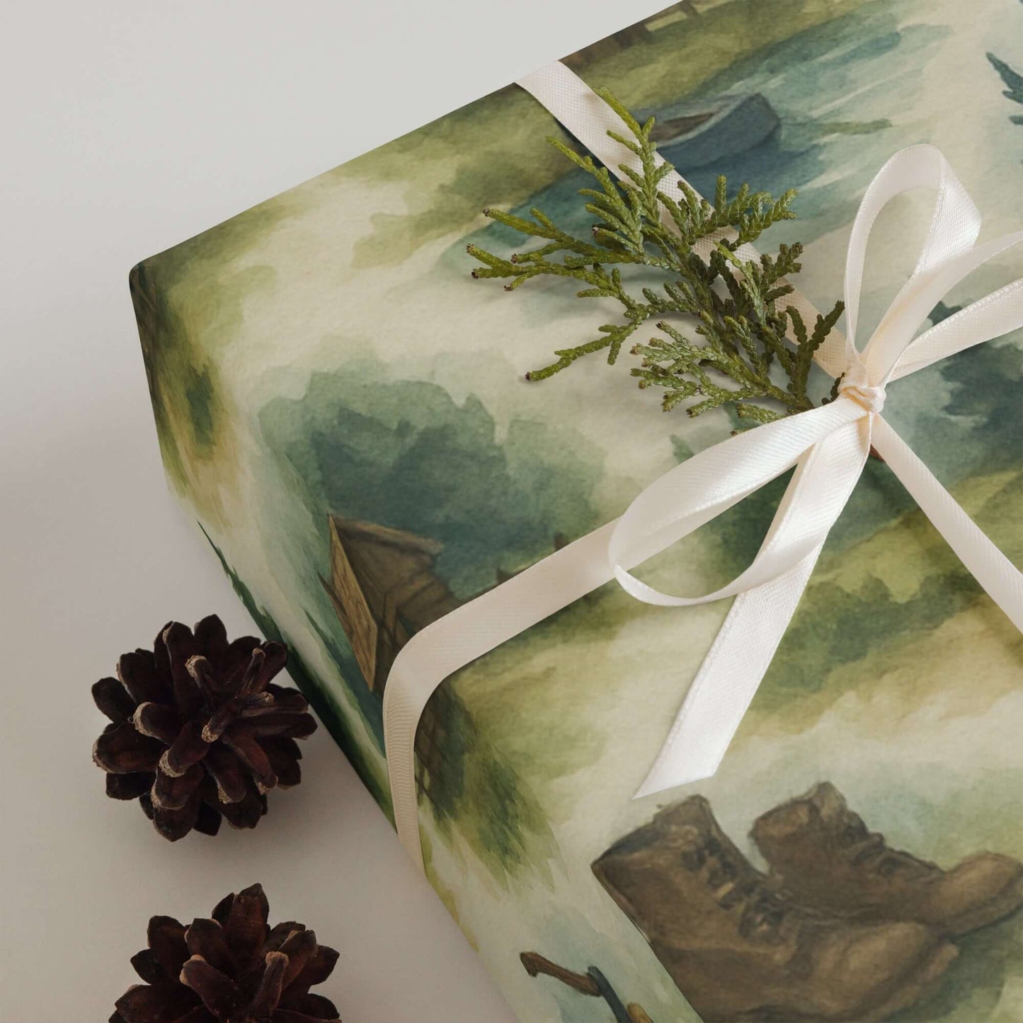Luxury Christmas wrapping paper featuring watercolor wilderness scenes with boots, pinecones, and greenery.