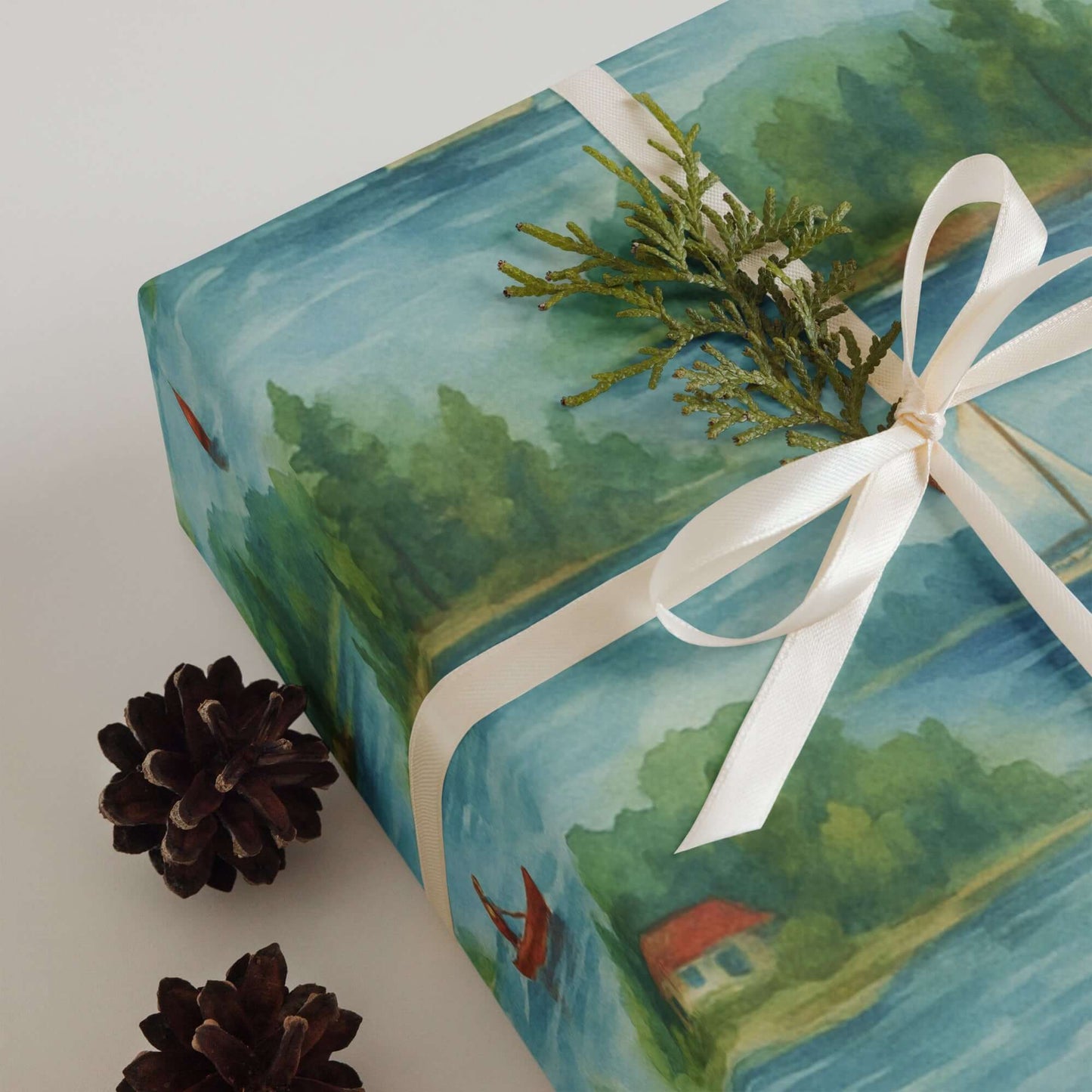 Watercolor design wrapping paper featuring lakeside scenes, topped with greenery and pinecones, ideal for luxury Christmas gift wrap.