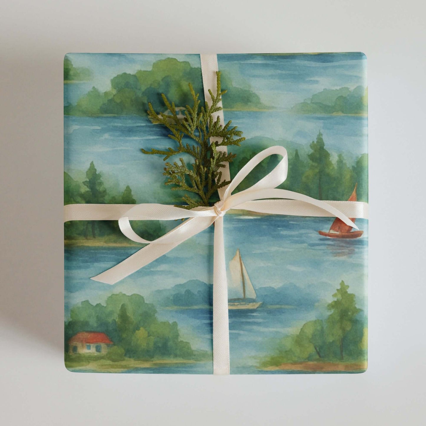 Lake Life watercolor wrapping paper featuring serene lakeside scenes, tied with a cream ribbon and greenery.