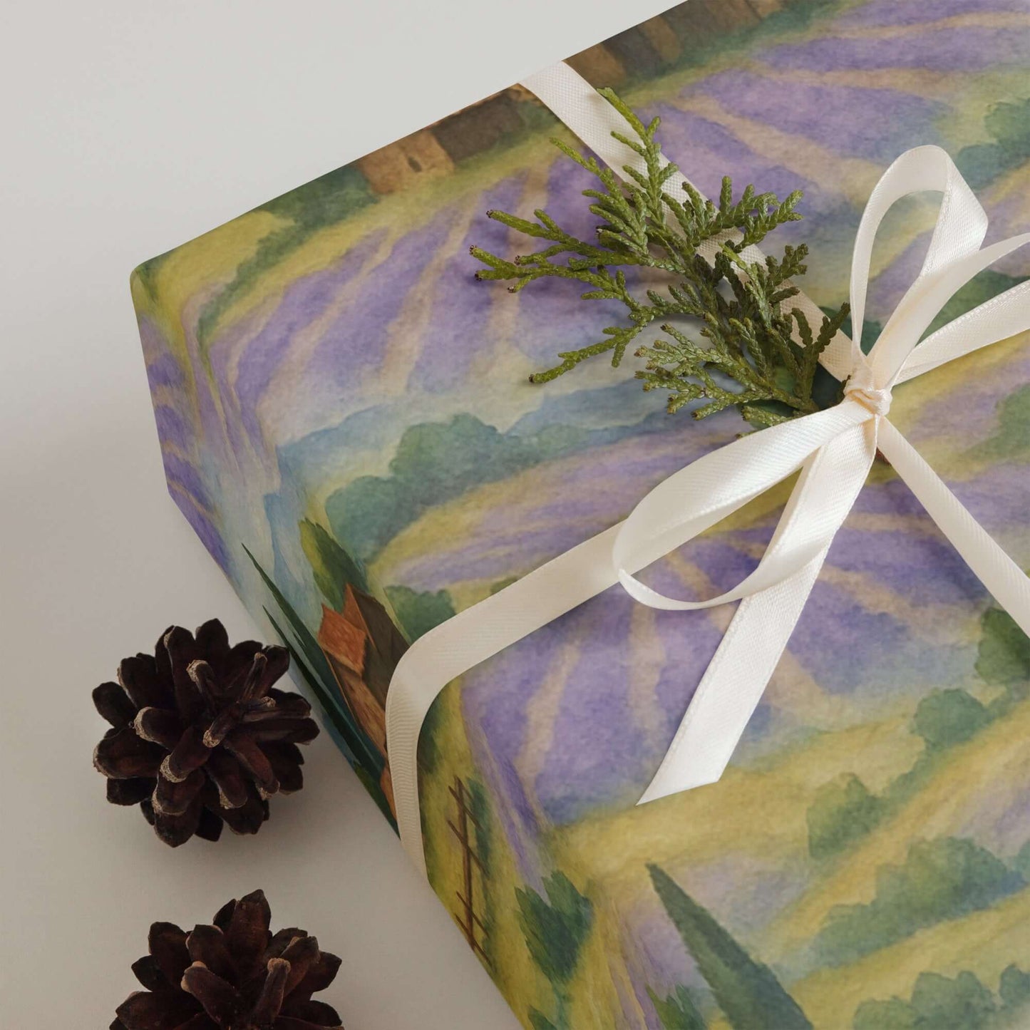 Luxury Christmas wrapping paper featuring watercolor lavender fields and rustic barns, styled with pinecones and greenery.