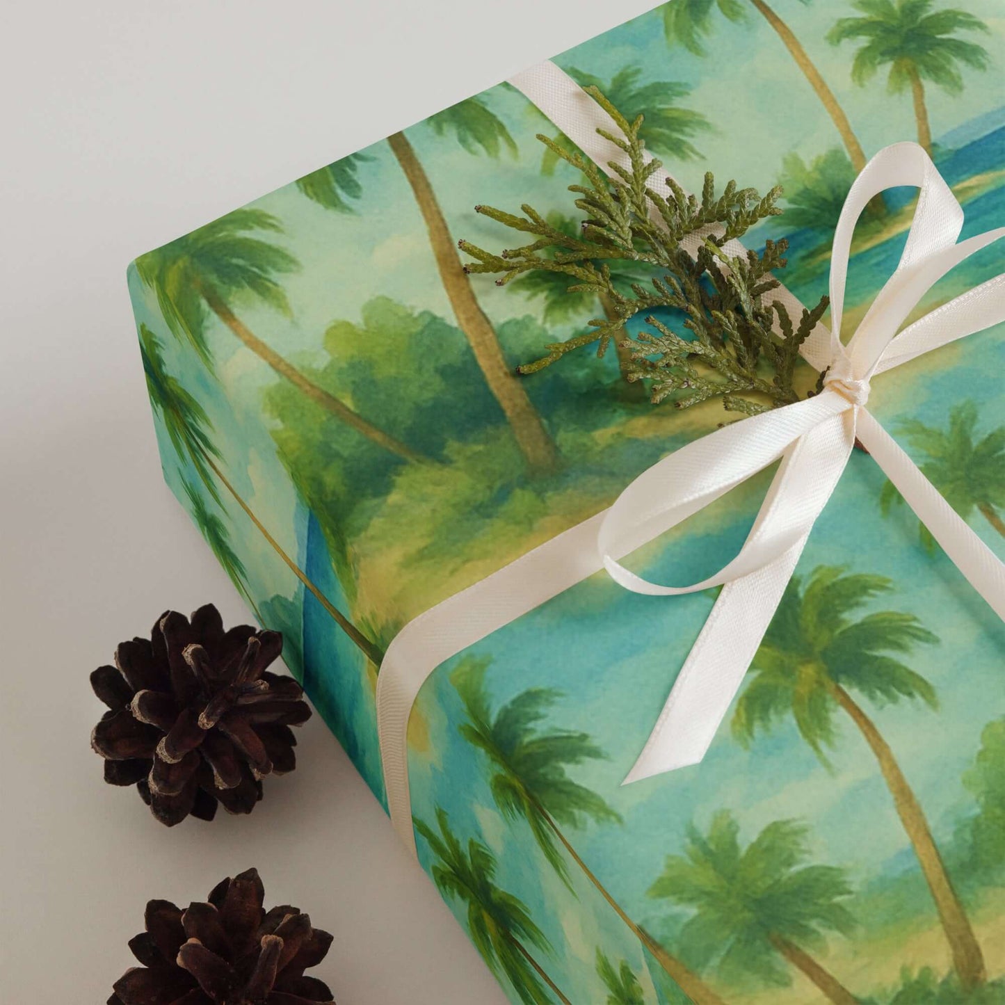 Luxury Christmas wrapping paper featuring tropical watercolor design with palm trees, tied with ribbon and enhanced by pinecones.