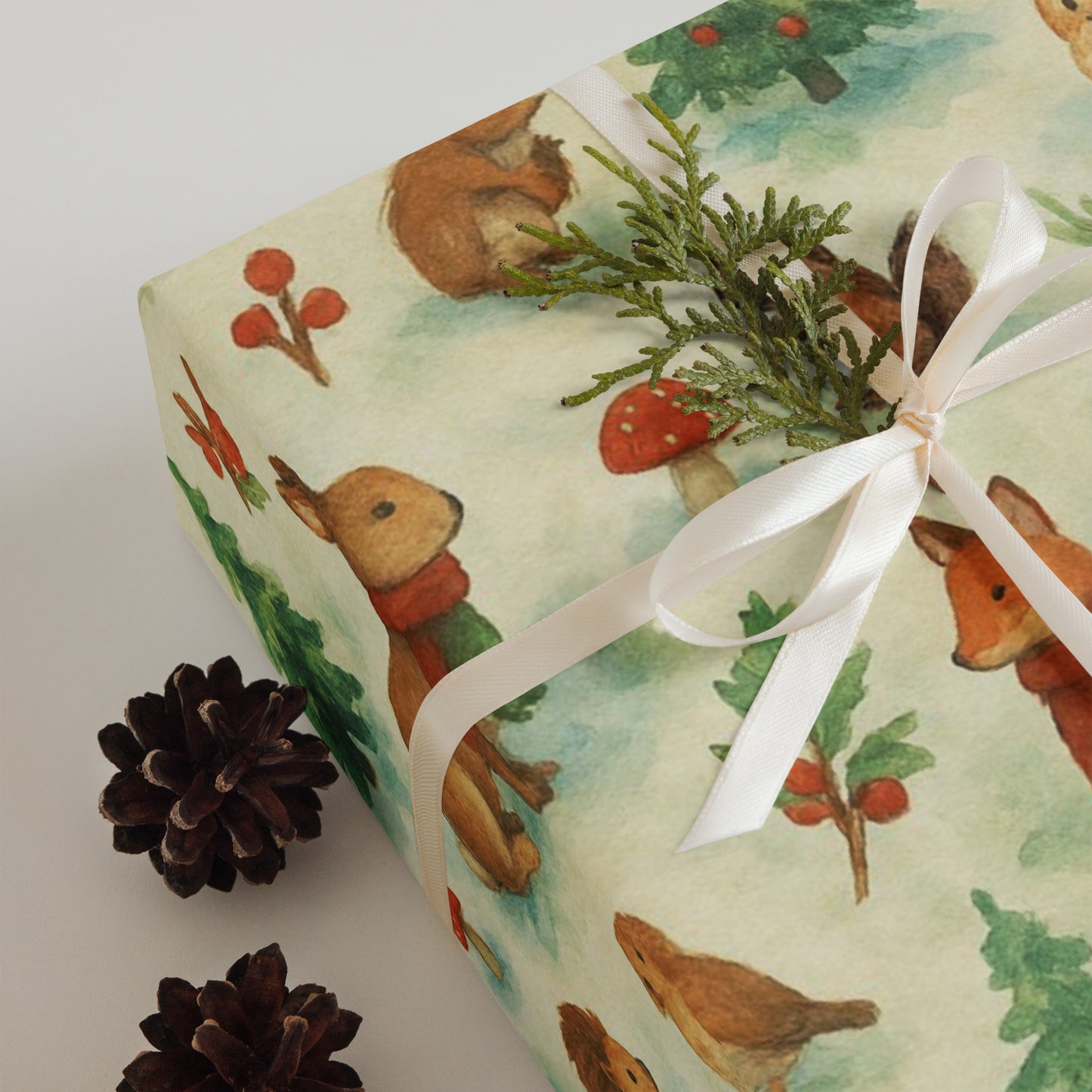 Luxury Christmas wrapping paper featuring watercolor woodland animals, styled with greenery and pinecones.