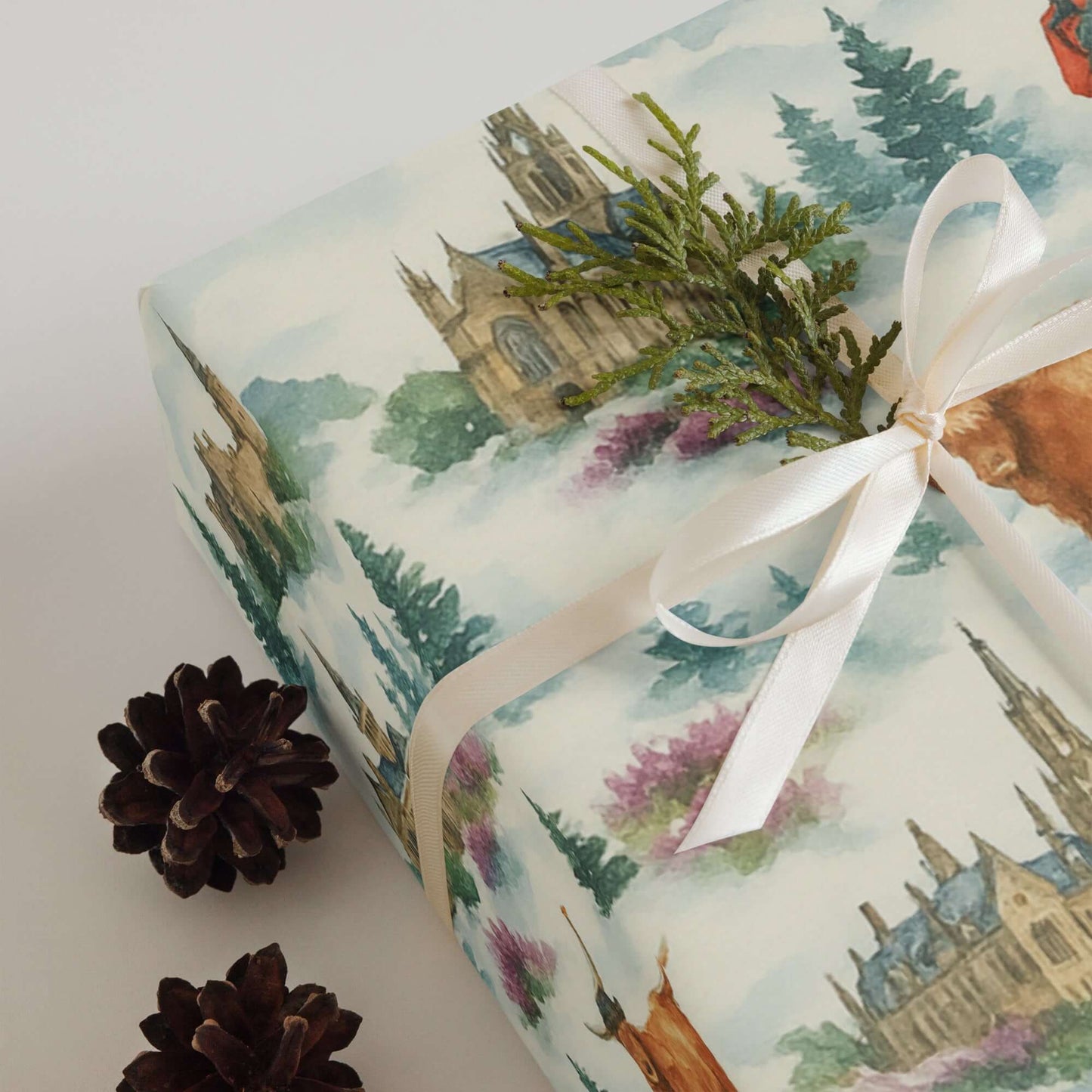 Luxury Christmas wrapping paper featuring watercolor Highland landscapes and Edinburgh Castle with festive foliage.