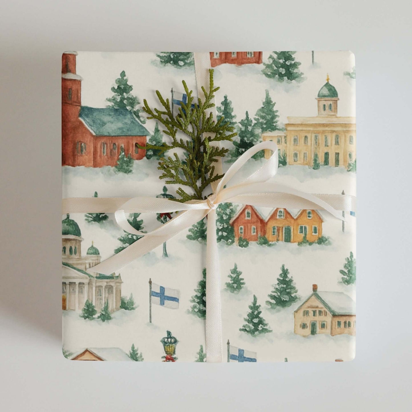 Luxury Christmas wrapping paper featuring Finnish winter scenes in watercolor design, adorned with greenery and ribbon.