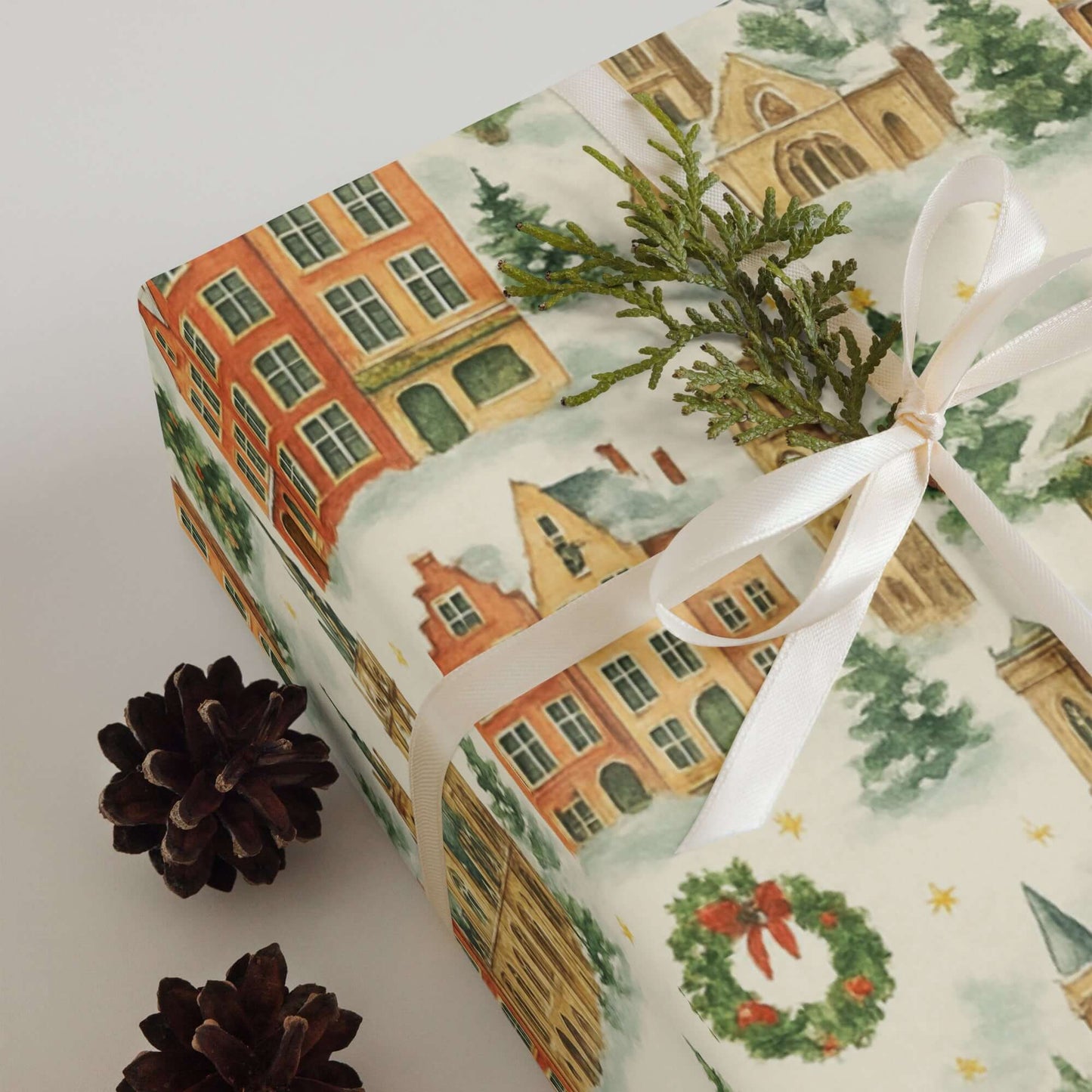 Luxury Christmas wrapping paper featuring watercolor European architecture design, adorned with pine and ribbon.