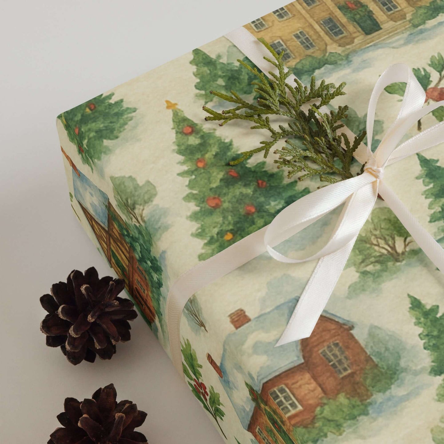 Luxury Christmas wrapping paper showcasing a watercolor design of a snowy village with pine accents and festive colors.