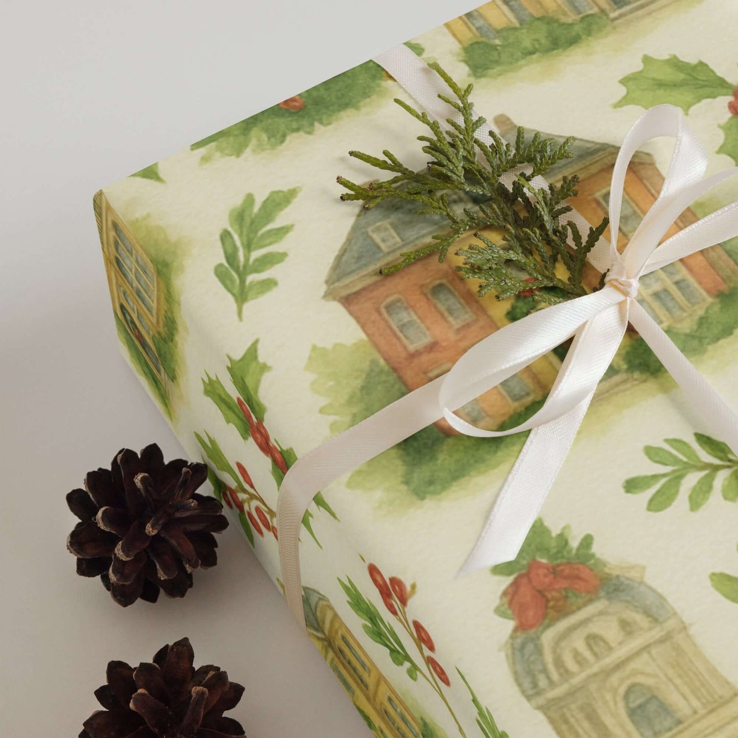 Luxury Christmas wrapping paper with watercolor townhouses, pine sprig, and bow, showcasing elegant holiday gift wrap.