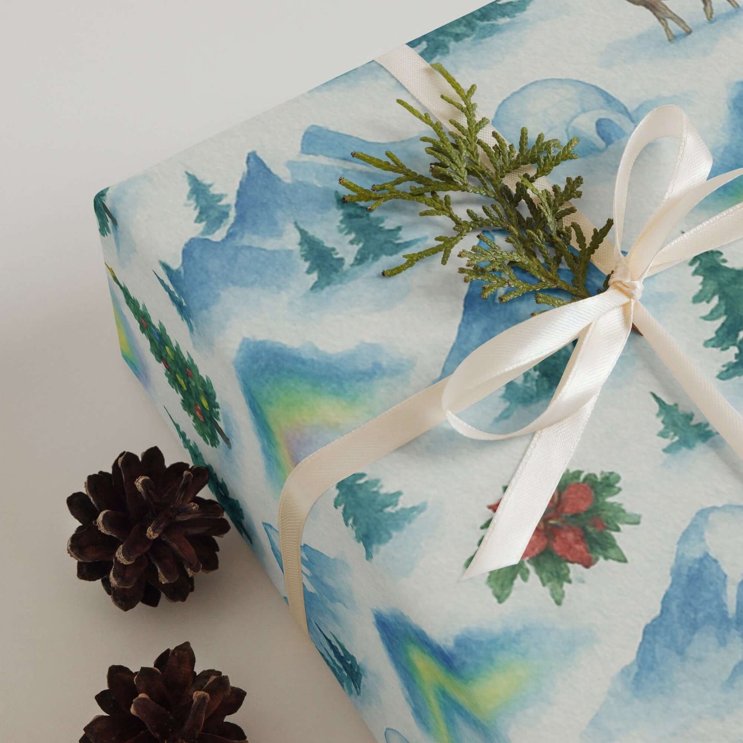 Luxury Christmas wrapping paper featuring watercolor Arctic mountains, northern lights, and holly, styled with pinecones.