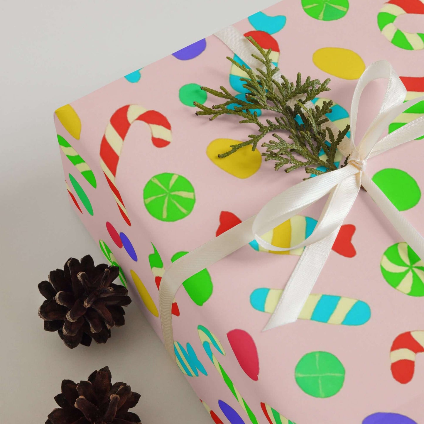 Luxury Christmas wrapping paper with colorful candy design, featuring peppermint swirls and candy canes on pink matte finish.