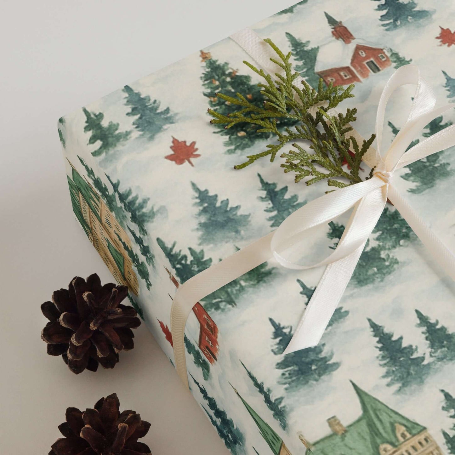 Luxury Christmas wrapping paper featuring watercolor winter scene of Canadian landscapes, tied with a satin ribbon.