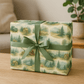 Rustic wilderness-themed luxury Christmas wrapping paper with green ribbon, featuring watercolor camping scenes.