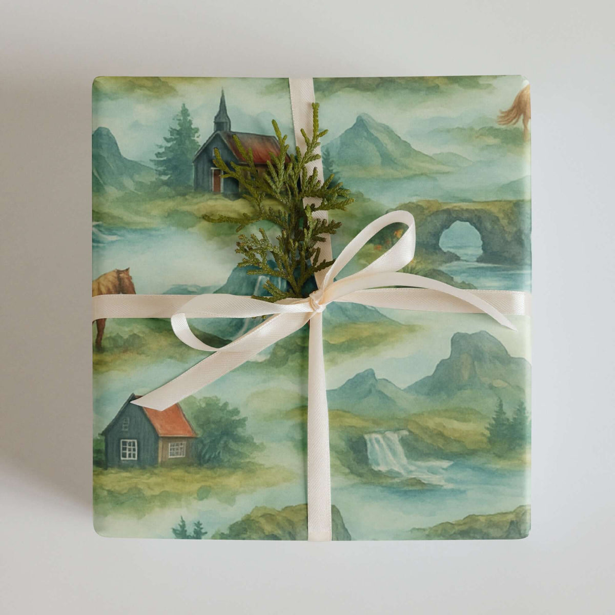 Iceland Wrapping Paper featuring hand-painted landscapes of waterfalls and Icelandic cottages, beautifully tied with a ribbon.