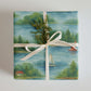 Lake Life watercolor wrapping paper featuring serene lakeside scenes, tied with a cream ribbon and greenery.