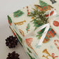 Nutcracker Christmas Wrapping Paper featuring holiday illustrations and decorated with a white ribbon and pine sprig.