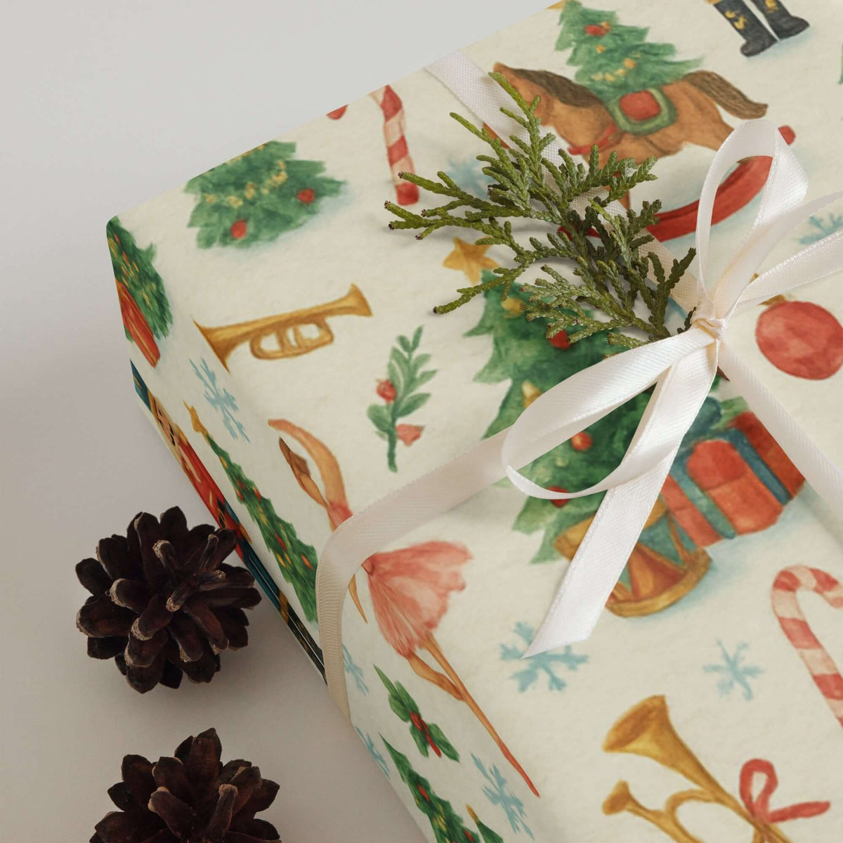 Nutcracker Christmas Wrapping Paper featuring holiday illustrations and decorated with a white ribbon and pine sprig.