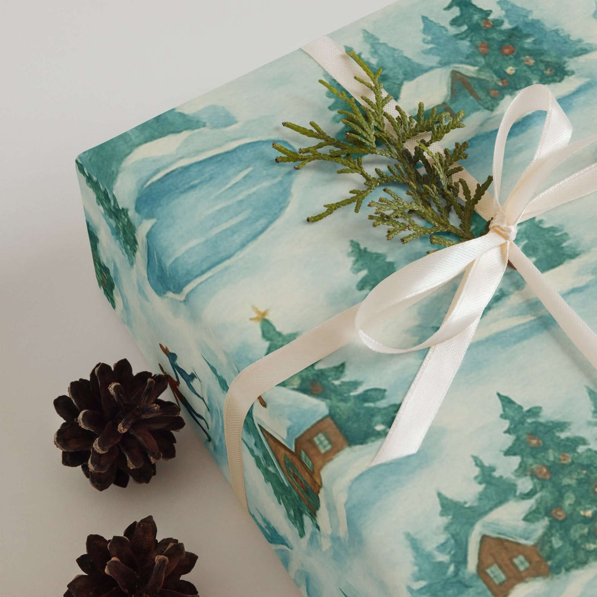 Skating Winter Christmas Wrapping Paper with snow-covered cabins, pine trees, and a ribbon.