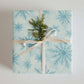 Snowflakes Christmas Wrapping Paper with blue snowflake design and green foliage embellishment