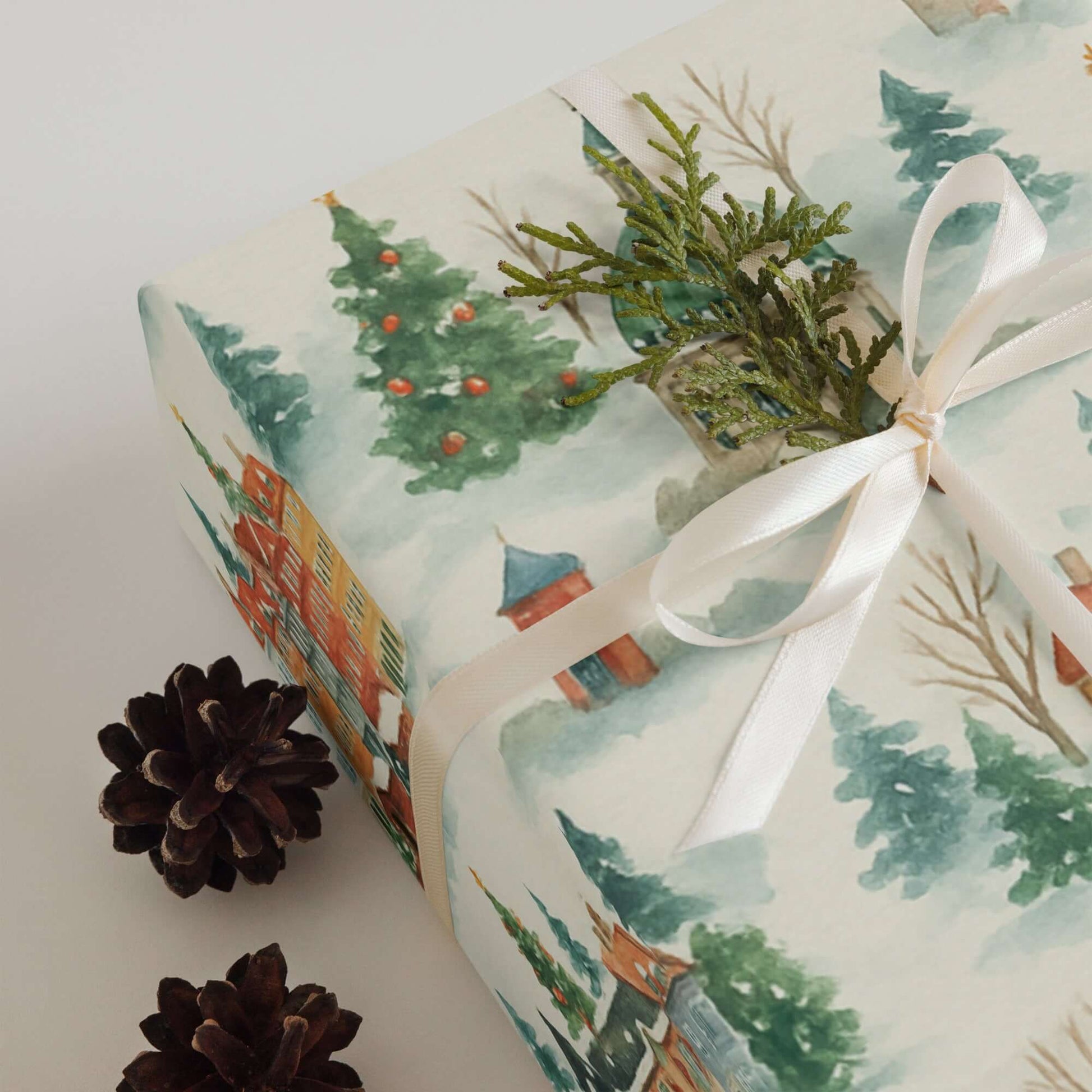 Luxury Christmas wrapping paper featuring watercolor illustration of snowy trees and colorful houses, elegantly tied with ribbon.