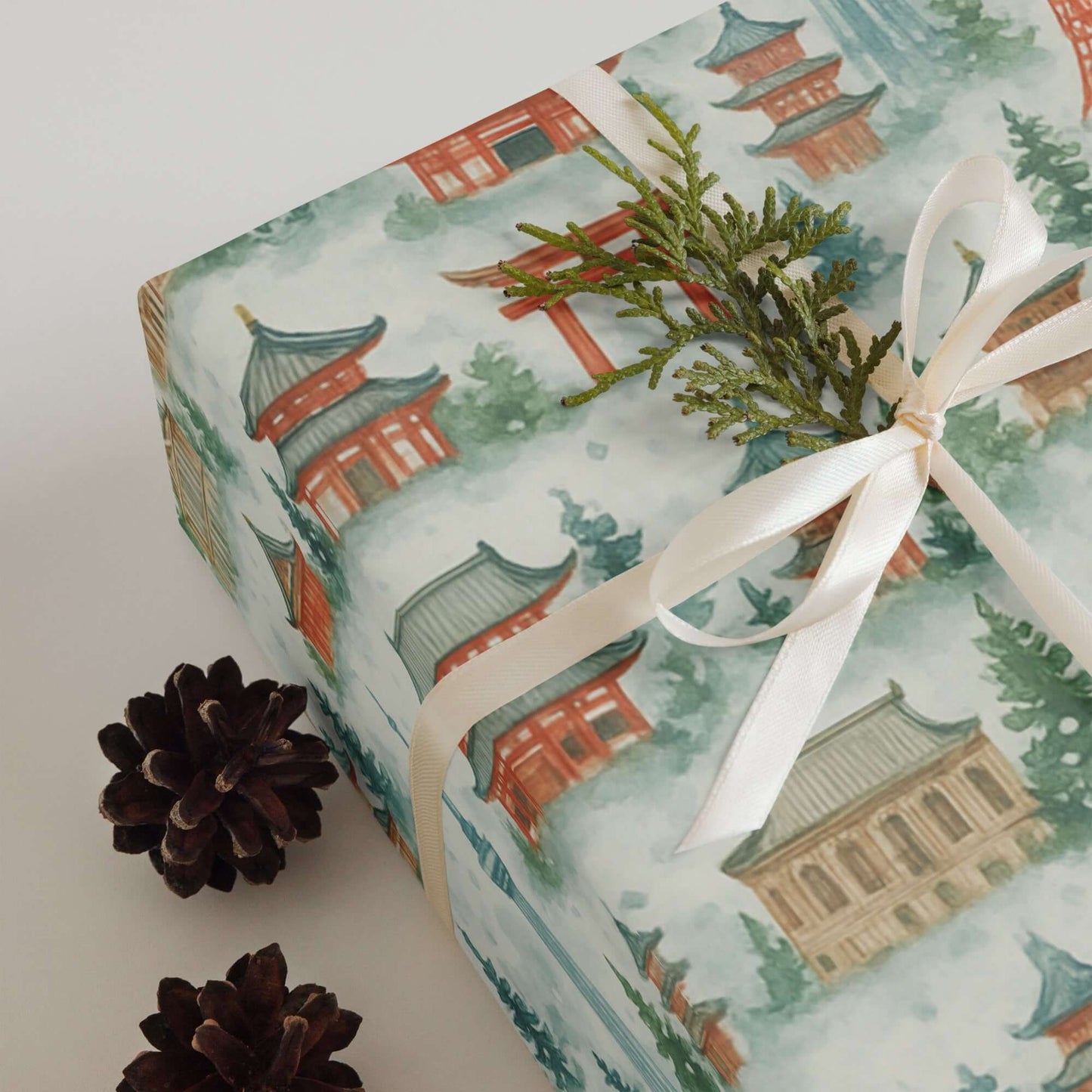 Luxury Christmas wrapping paper featuring watercolor Japanese temples, adorned with a delicate ribbon and pine sprig.