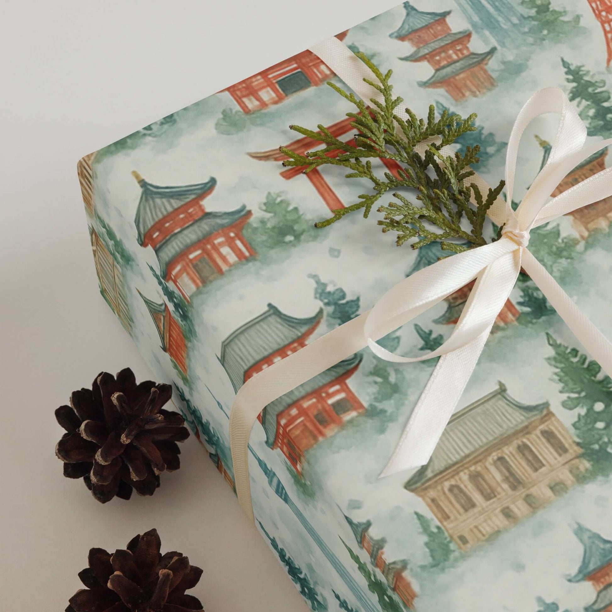 Luxury Christmas wrapping paper featuring watercolor Japanese temples, adorned with a delicate ribbon and pine sprig.