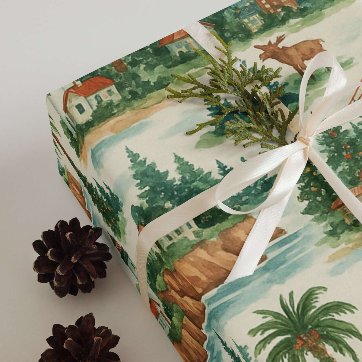 Luxury Christmas wrapping paper featuring watercolor coastal scenery with pinecones and greenery decoration.