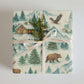 Luxury Rockies Christmas wrapping paper featuring watercolor mountain scenes and rustic cabins with holiday elements.