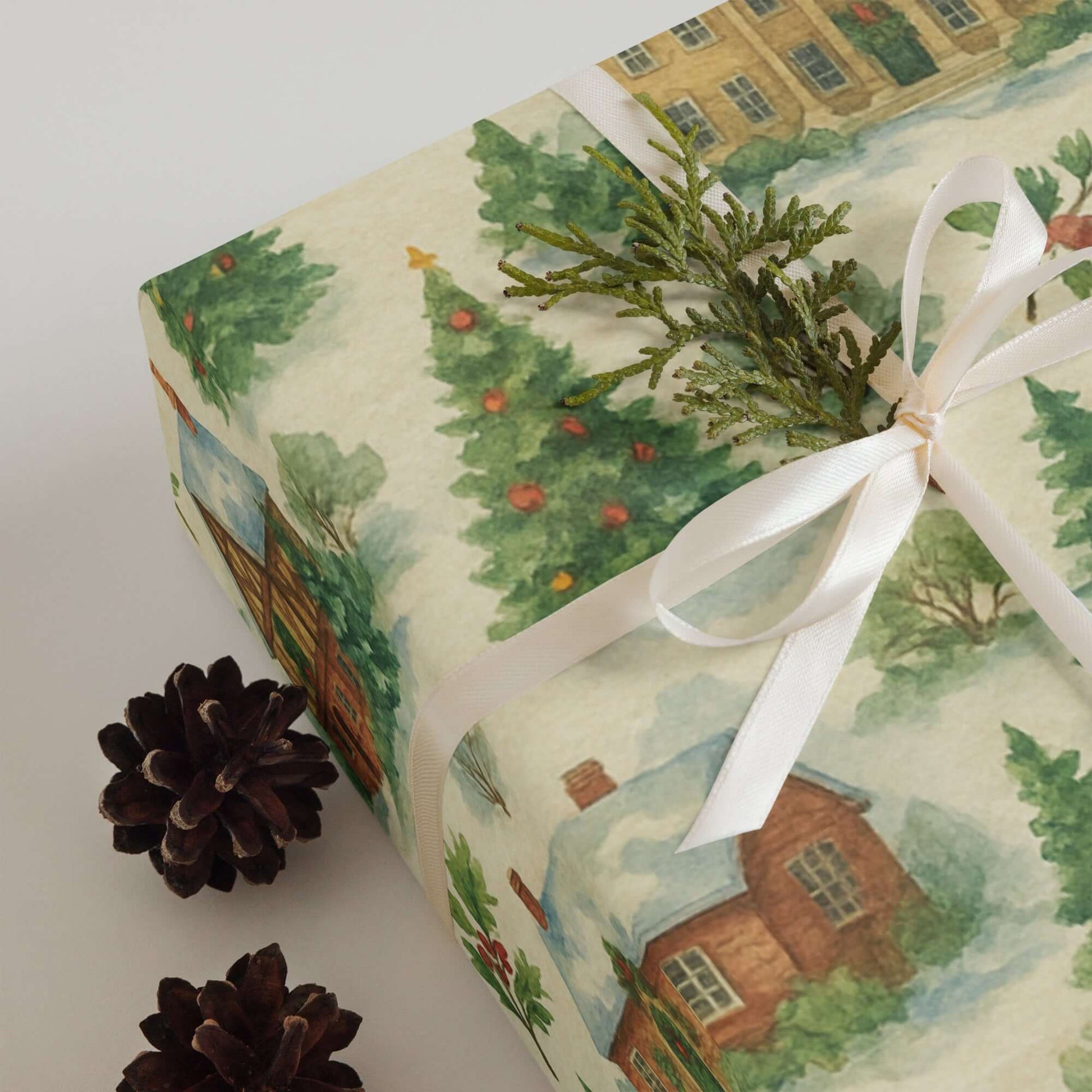 Luxury Christmas wrapping paper showcasing a watercolor design of a snowy village with pine accents and festive colors.