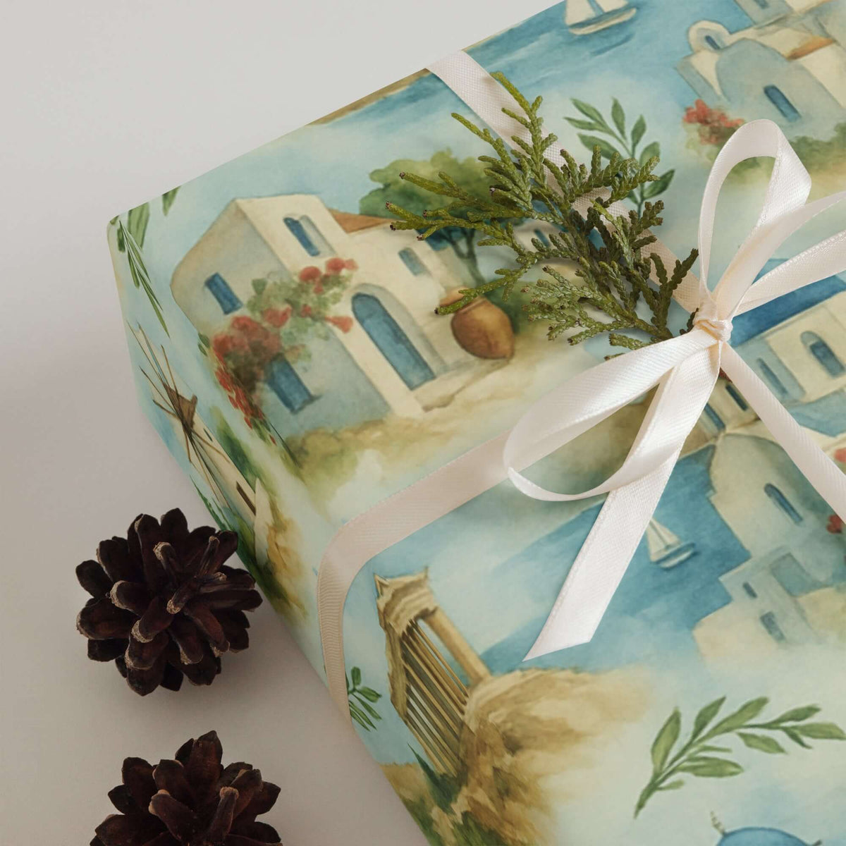 Greece Wrapping Paper featuring Mediterranean scenes with whitewashed houses, blue domes, and olive branches on a gift.